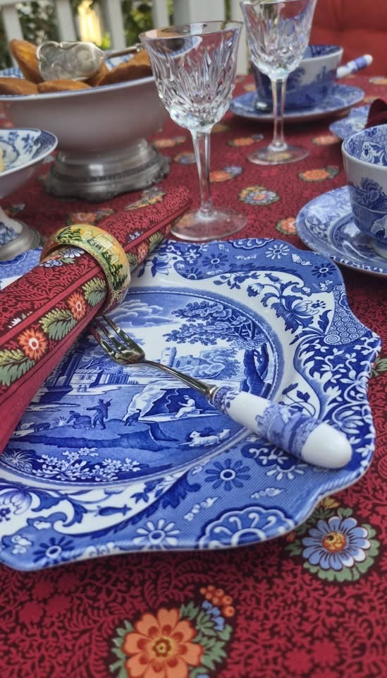 青花瓷餐盘与餐具的近景,背景是水晶杯和糕点